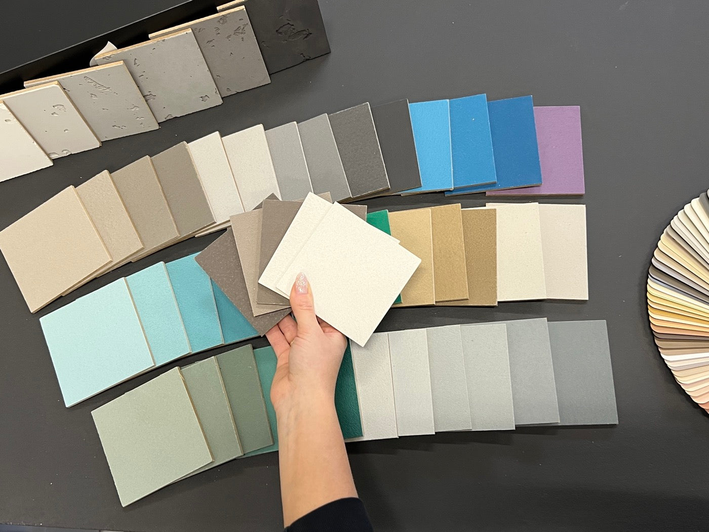 betonPure Farbmuster in der Hand vor der Farbpalette